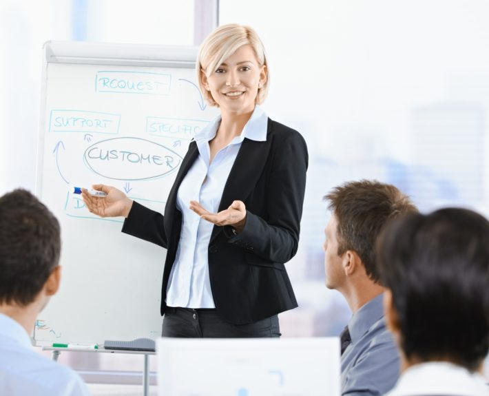 Business people sitting on presentation at office. Businesswoman presenting on whiteboard.